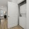 Compact laundry nook featuring a stackable washer and dryer unit, with a utility shelf beside it.